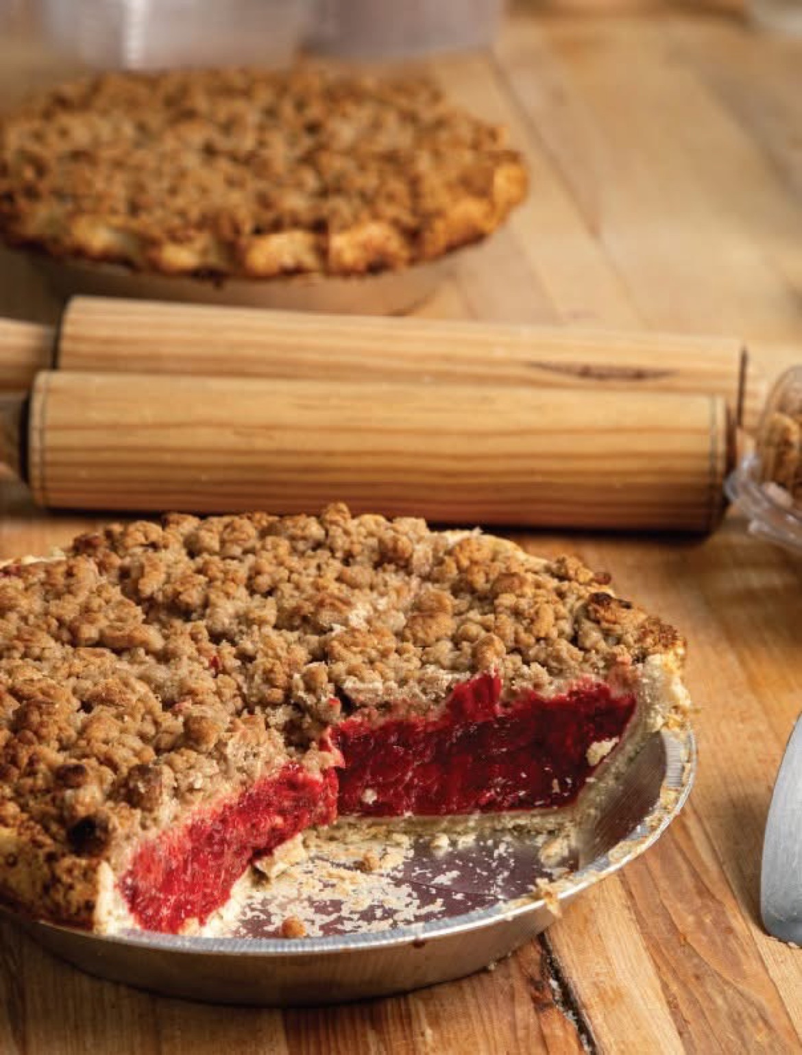 A cherry crumble pie with a slice cut and served, showing bright red cherry filling